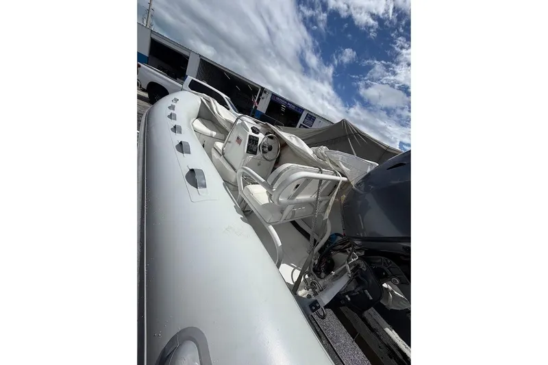 Slide: The Image of 2010 Nautica RIB 14 inflatable boat with steering console, parked outdoors under cloudy sky. - 4
