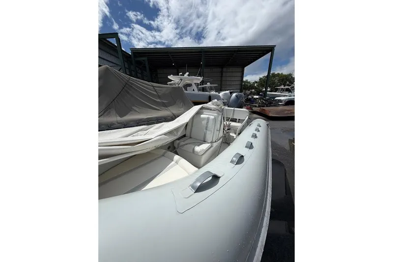 Slide: The Image of 2010 Nautica RIB 14 inflatable boat in storage, partially covered, under a cloudy sky. - 5
