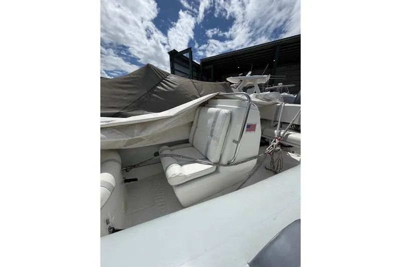 Slide: The Image of 2010 Nautica RIB 14 boat with white seating, docked under a partly cloudy sky. - 7