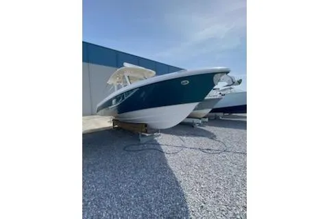 Slide: The Image of 2019 Everglades 335 Center Console boat displayed outdoors near a warehouse. - 2