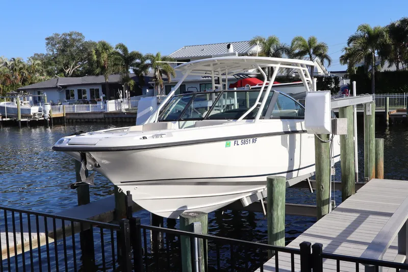 The Image of 2016 Boston Whaler 270 Vantage boat docked by waterfront homes with palm trees. - 0