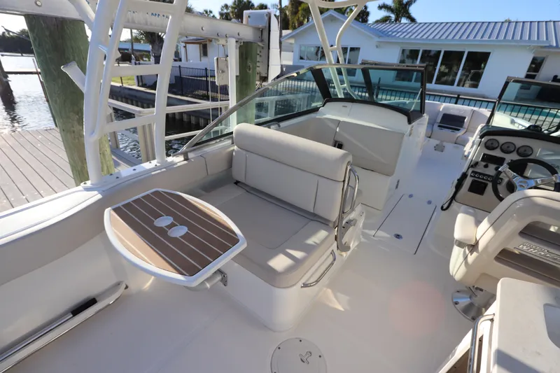 Slide: The Image of 2016 Boston Whaler 270 Vantage boat interior with seating and helm, docked by waterfront. - 14