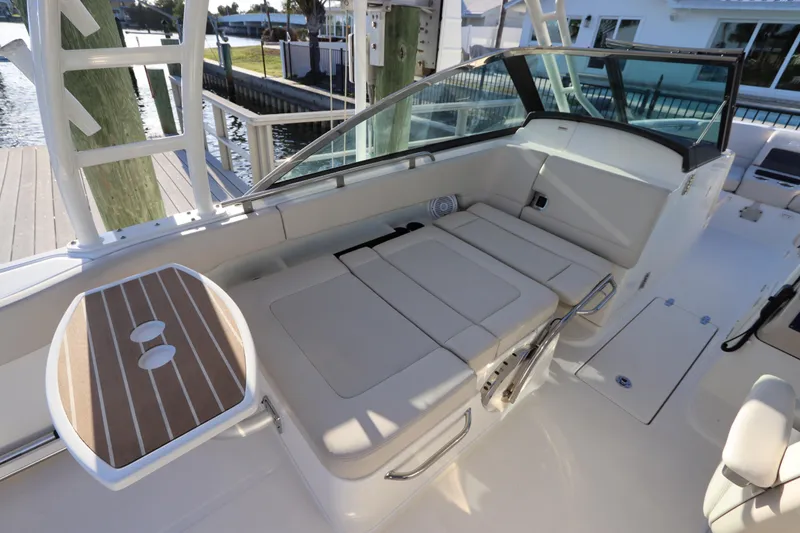 Slide: The Image of 2016 Boston Whaler 270 Vantage boat interior with seating and table, docked by the water. - 16