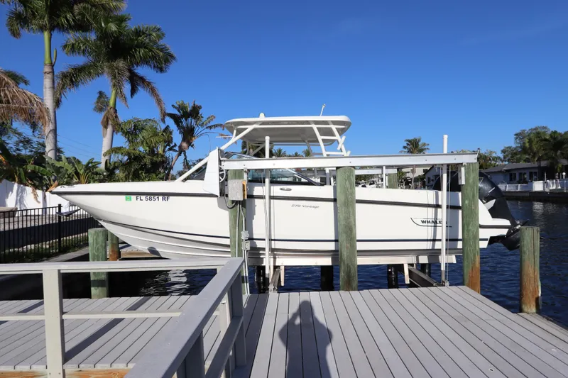 Slide: The Image of 2016 Boston Whaler 270 Vantage boat docked by palm trees under clear blue sky. - 2