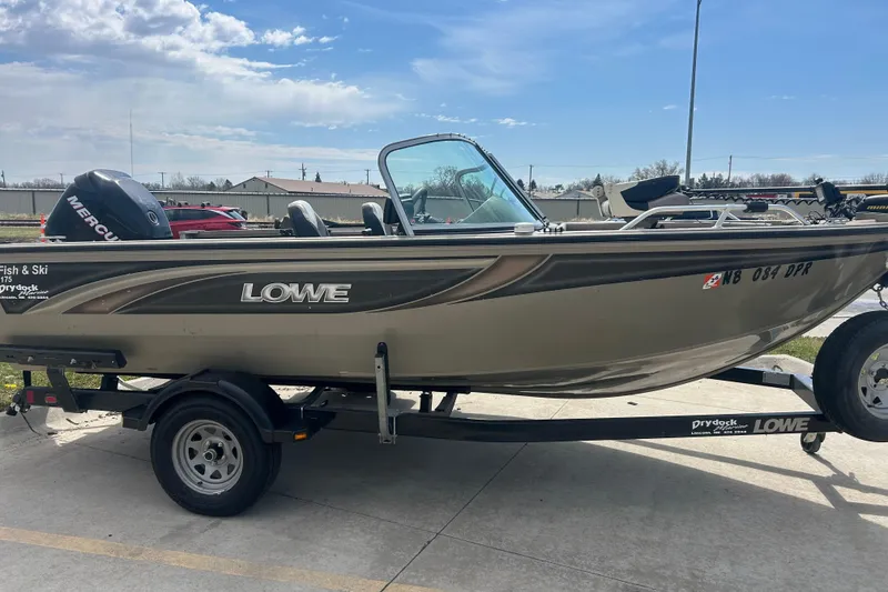 Slide: The Image of 2006 Lowe Fish & Ski 175 boat on trailer, parked outdoors under a clear sky. - 2