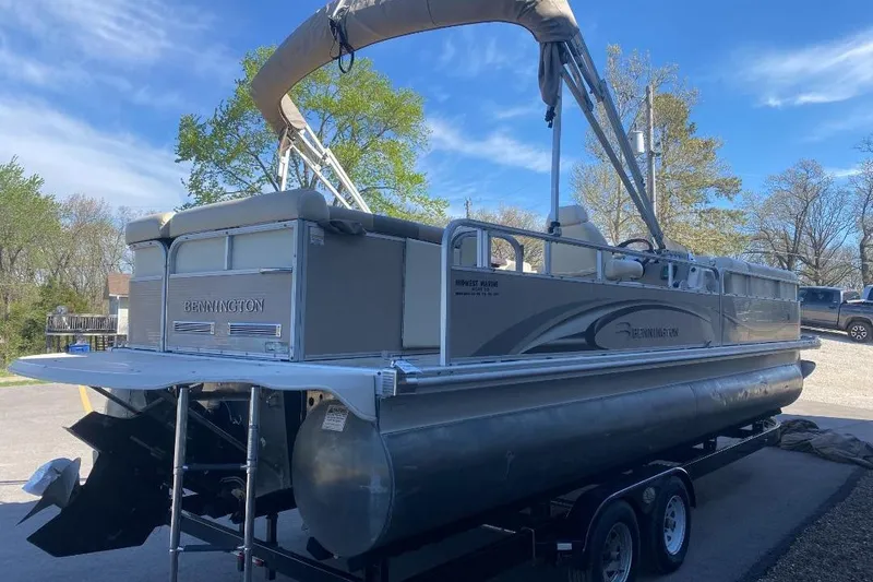 Slide: The Image of 2008 Bennington 2575RL I/O pontoon boat on trailer, parked outdoors under blue sky. - 2