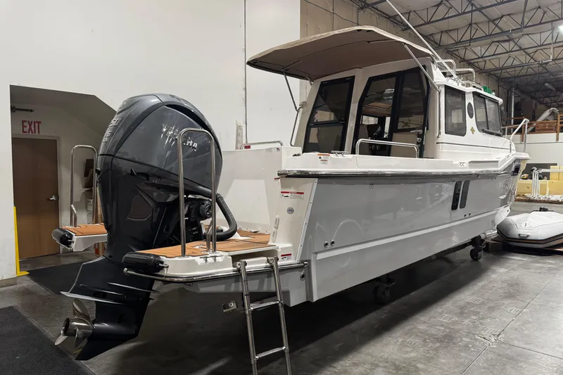 Slide: The Image of 2026 Ranger Tugs R-25 boat with outboard motor in a warehouse setting. - 3