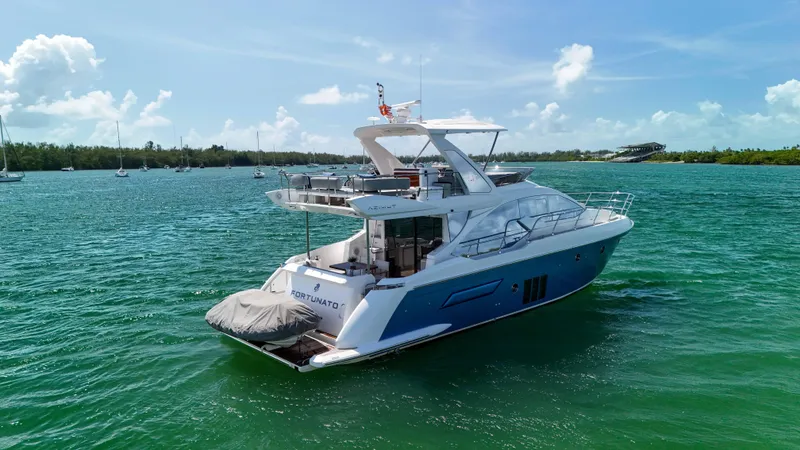 Slide: The Image of 2016 Azimut 50 Flybridge yacht on serene blue waters under a clear sky. - 16
