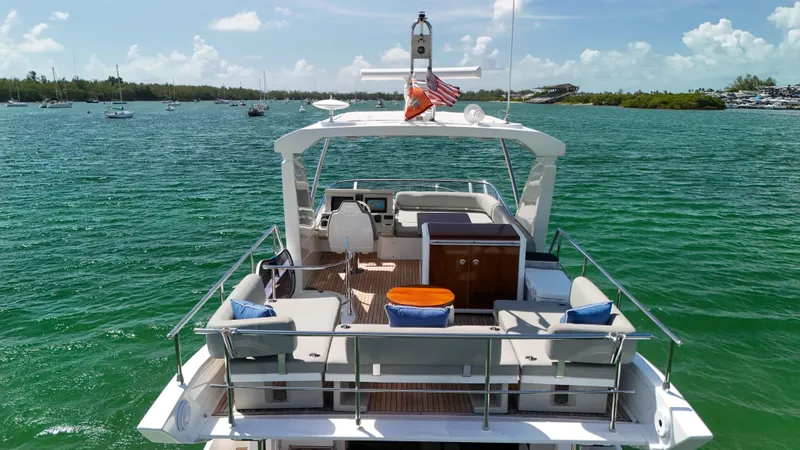 Slide: The Image of 2016 Azimut 50 Flybridge yacht on serene green waters, featuring spacious deck and seating. - 22