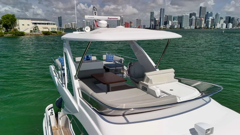 Slide: The Image of 2016 Azimut 50 Flybridge yacht cruising near city skyline, featuring spacious deck and modern design. - 27