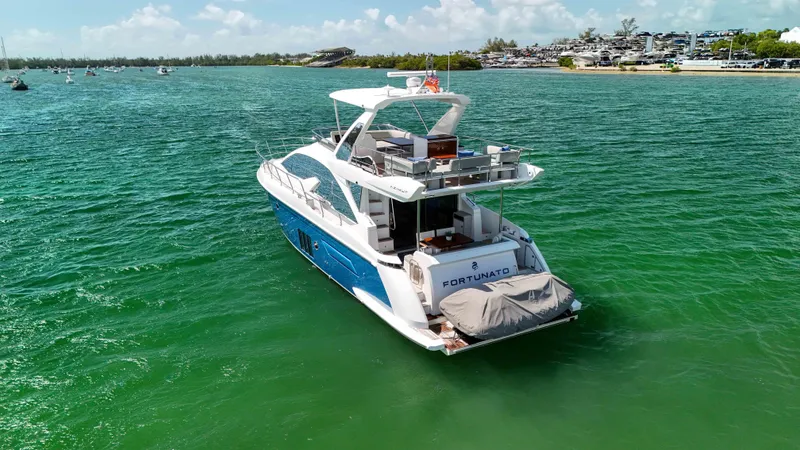 Slide: The Image of Azimut 50 Flybridge 2016 yacht cruising on clear green waters near a scenic shoreline. - 4