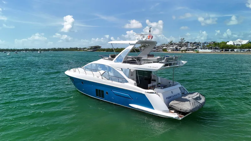 Slide: The Image of 2016 Azimut 50 Flybridge yacht cruising on clear blue waters under a sunny sky. - 6