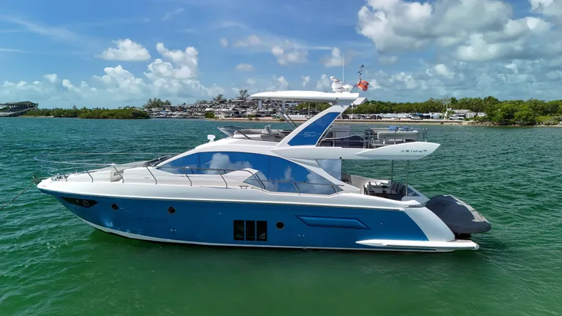 Slide: The Image of 2016 Azimut 50 Flybridge yacht on serene water under a partly cloudy sky. - 8