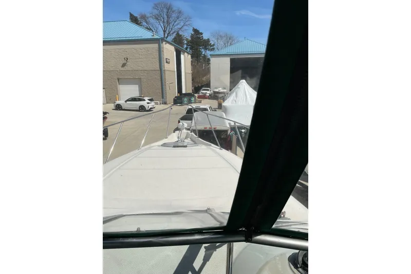 Slide: The Image of 1997 Maxum 2700 SCR boat docked near storage buildings and parked cars. - 13