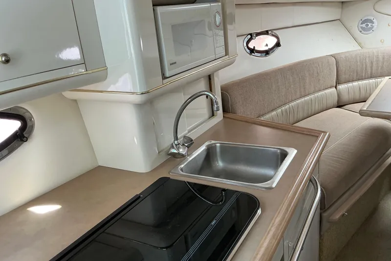 Slide: The Image of 1997 Maxum 2700 SCR boat interior with kitchenette, sink, microwave, and seating area. - 15