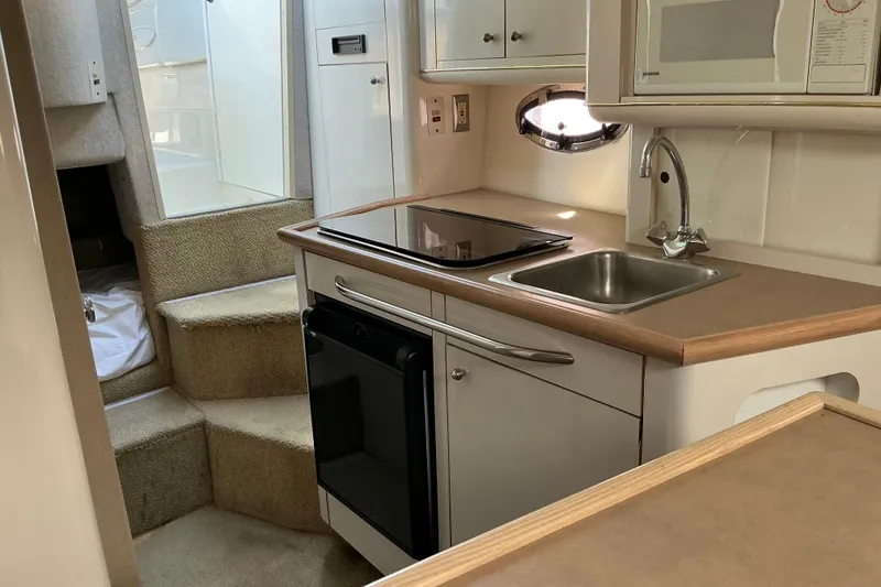 Slide: The Image of Interior of 1997 Maxum 2700 SCR boat featuring compact kitchen with stove and sink. - 18