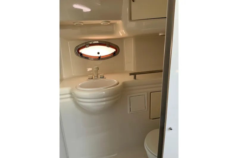 Slide: The Image of 1997 Maxum 2700 SCR boat bathroom with sink, porthole, and storage cabinets. - 21