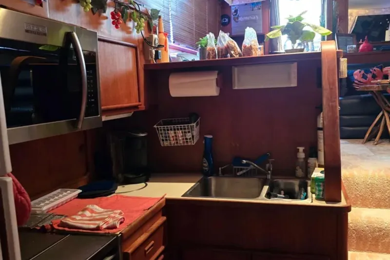 Slide: The Image of 1987 Chris-Craft 427 Catalina kitchen interior with microwave, sink, and wooden cabinetry. - 11