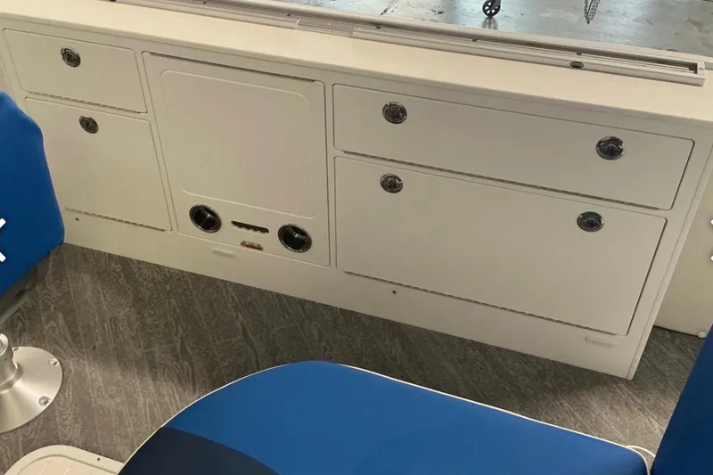 Slide: The Image of Interior of 2025 JC SportAngler 26TT HTH boat with blue seating and storage compartments. - 18