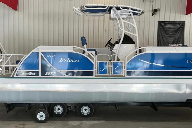Slide: The Image of 2025 JC SportAngler 26TT HTH pontoon boat with blue and white design in showroom. - 5