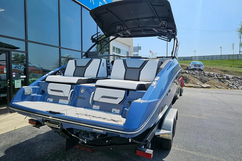 Slide: The Image of 2023 Yamaha Boats 255XD in blue, parked outside a showroom on a sunny day. - 3