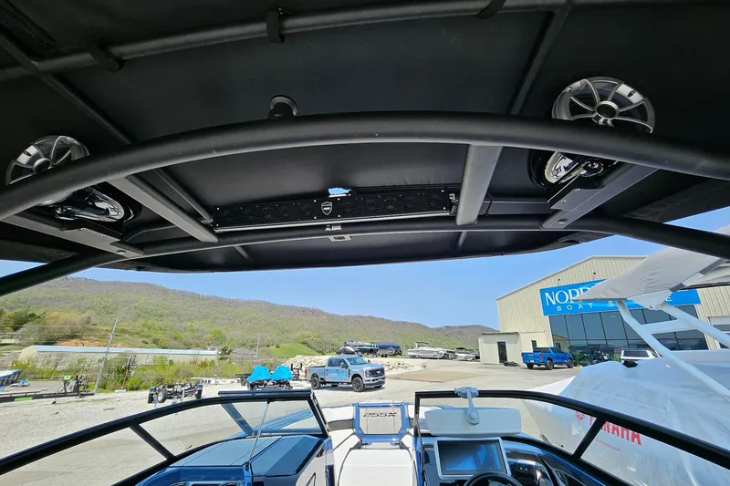 Slide: The Image of 2023 Yamaha Boats 255XD interior view with speakers and dashboard, outdoors at dealership. - 4
