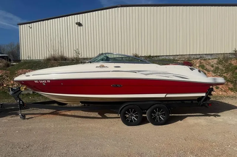 The Image of 2005 Sea Ray 220 Sundeck boat on trailer, red and white exterior, parked outdoors. - 0