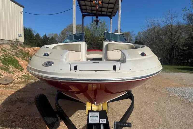 Slide: The Image of 2005 Sea Ray 220 Sundeck boat on trailer, parked outdoors under clear blue sky. - 2