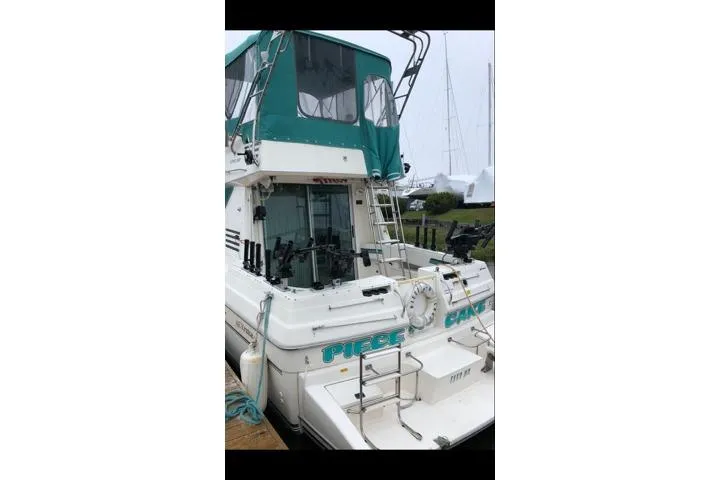Slide: The Image of 1994 Cruisers Yachts 3380 Esprit docked, featuring green canopy and fishing equipment. - 1