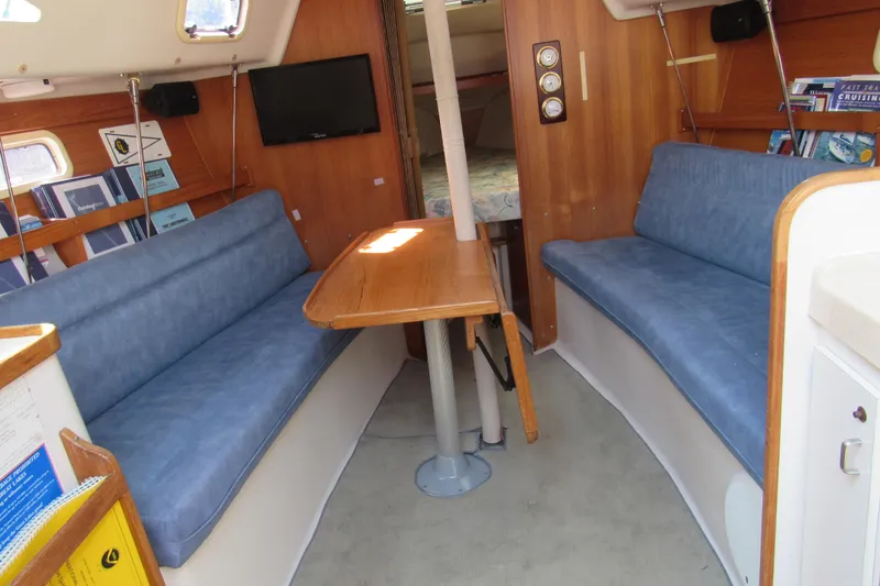Slide: The Image of Interior of a 1997 Catalina 28 MkII sailboat with blue seating and wooden table. - 11