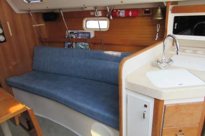 Slide: The Image of Interior of a 1997 Catalina 28 MkII sailboat with blue seating and compact kitchenette. - 13