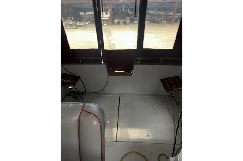 Slide: The Image of Interior of a 1990 Thompson 250 Daytona Mid Cabin boat, featuring seating and windows. - 12