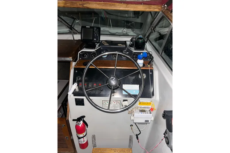 Slide: The Image of 1990 Thompson 250 Daytona Mid Cabin boat helm with steering wheel and navigation equipment. - 14