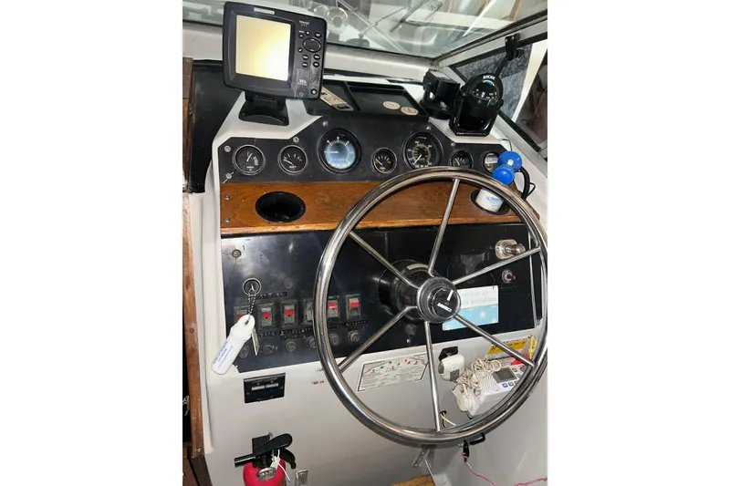 Slide: The Image of 1990 Thompson 250 Daytona Mid Cabin boat dashboard with steering wheel and navigation instruments. - 17
