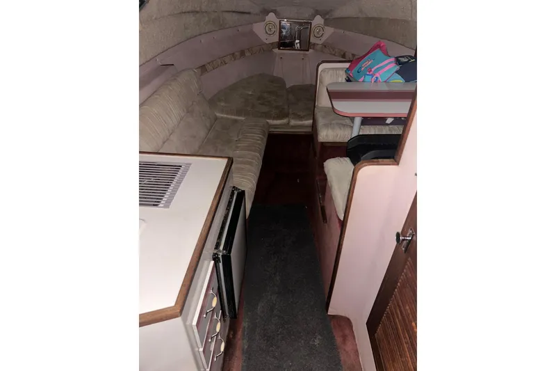 Slide: The Image of 1990 Thompson 250 Daytona Mid Cabin interior with seating and compact kitchenette. - 18