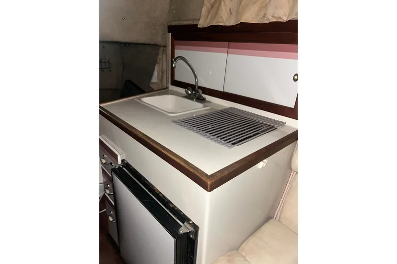 Slide: The Image of 1990 Thompson 250 Daytona Mid Cabin kitchenette with sink and mini fridge. - 19