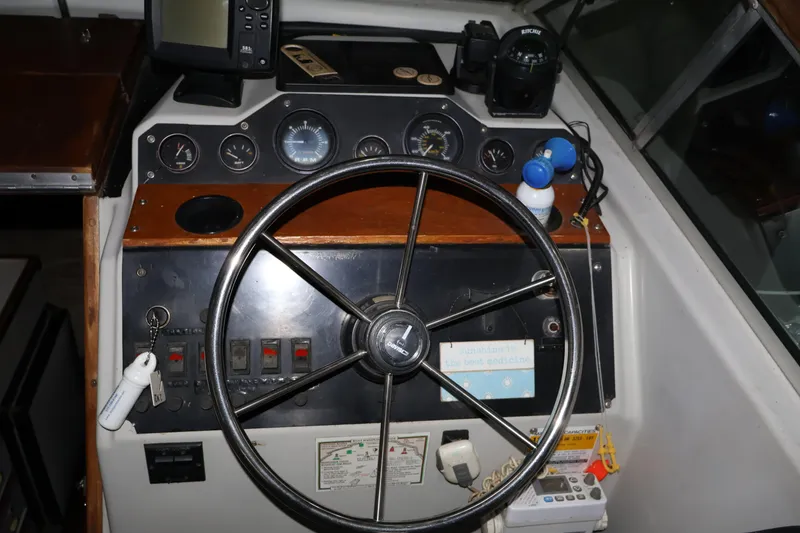 Slide: The Image of 1990 Thompson 250 Daytona Mid Cabin boat dashboard with steering wheel and navigation instruments. - 24