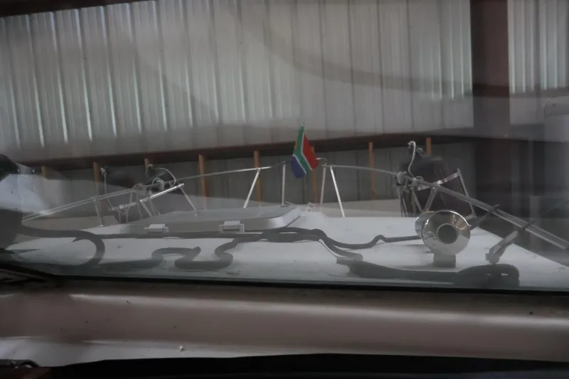 Slide: The Image of 1990 Thompson 250 Daytona Mid Cabin boat in storage, featuring a flag and nautical equipment. - 25