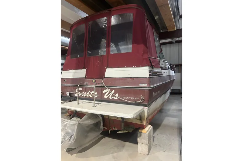 Slide: The Image of 1990 Thompson 250 Daytona Mid Cabin boat with maroon cover in storage. - 3