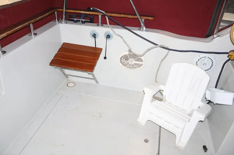 Slide: The Image of 1990 Thompson 250 Daytona Mid Cabin boat interior with white chair and wooden bench. - 34