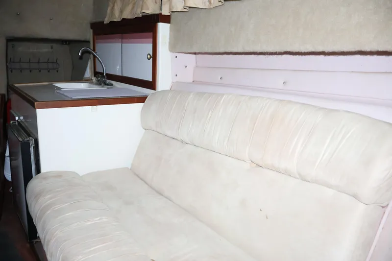 Slide: The Image of Interior of 1990 Thompson 250 Daytona Mid Cabin with beige seating and kitchenette. - 38