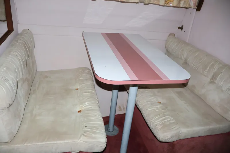 Slide: The Image of 1990 Thompson 250 Daytona Mid Cabin interior with beige seating and striped table. - 41