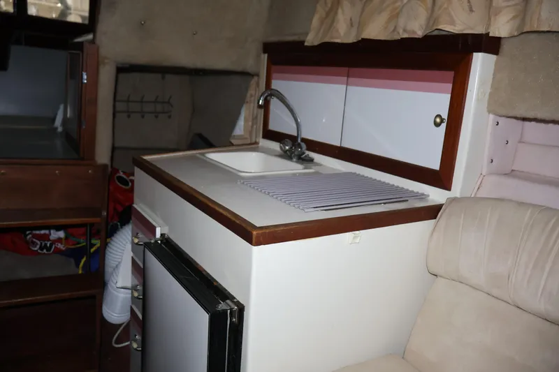 Slide: The Image of 1990 Thompson 250 Daytona Mid Cabin interior with kitchenette and seating area. - 44