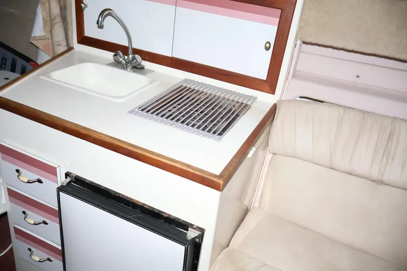 Slide: The Image of 1990 Thompson 250 Daytona Mid Cabin interior with sink, stove, and seating area. - 45