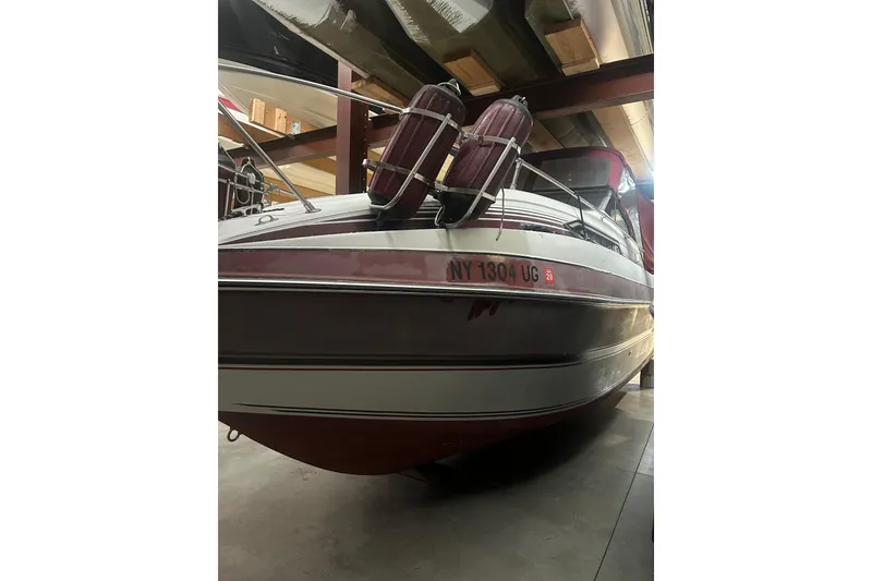 Slide: The Image of 1990 Thompson 250 Daytona Mid Cabin boat in storage, featuring maroon and white exterior. - 8
