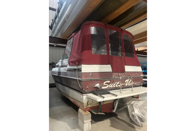 Slide: The Image of 1990 Thompson 250 Daytona Mid Cabin boat with maroon canopy in storage. - 9