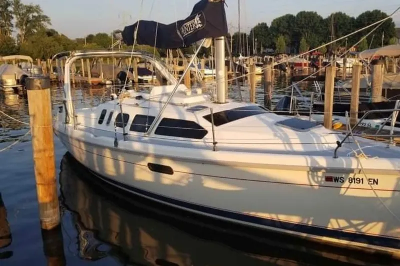 Slide: The Image of 1998 Hunter 310 sailboat docked at a marina, surrounded by calm water and other boats. - 2