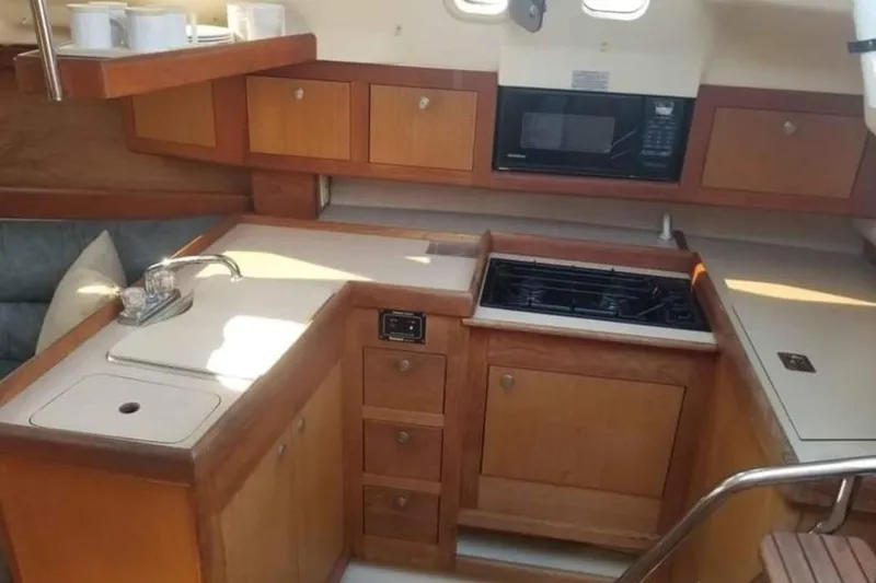 Slide: The Image of Compact kitchen in a 1998 Hunter 310 sailboat with wooden cabinets and modern appliances. - 6