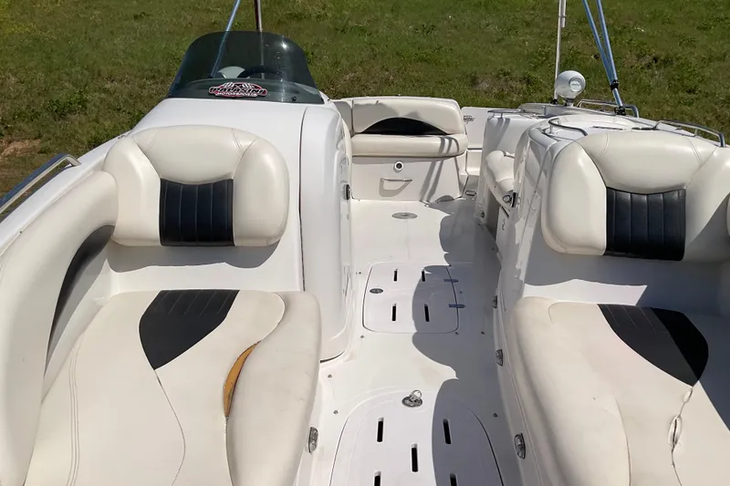 Slide: The Image of 2011 Tahoe 225 boat interior with white and black seating, grassy background. - 16