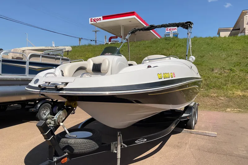 Slide: The Image of 2011 Tahoe 225 boat on trailer near Exxon station under clear blue sky. - 2